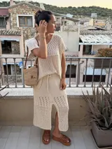 Pollera midi color crudo, tejida en hilo de algodón con calados horizontales. Tiene silueta recta, abertura frontal, elástico en la cintura y tiras regulables.