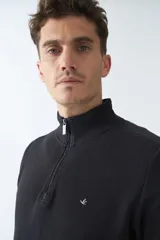 Buzo de algodón con cuello alto y cierre frontal parcial. Presenta puños y ruedo acanalados, con un pequeño logo bordado en el pecho.