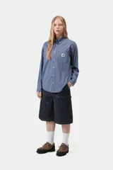 Camisa de manga larga Carhartt WIP modelo Groff, de corte regular y confeccionada en popelina de algodón ligera con estampado de cuadros. Cuenta con cierre frontal de botones, cuello con botones y un bolsillo aplicado en el pecho con etiqueta cuadrada tejida de la marca.