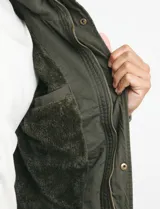 Campera de abrigo color verde militar, con capucha desmontable forrada, cierre frontal con cremallera y botones a presión. Cuenta con múltiples bolsillos: dos en el pecho con cierre, dos en la cintura con botones y un bolsillo en la manga. El interior está forrado para mayor calidez.