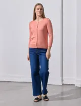 Cardigan blanco de tejido fino con abertura central y botones.