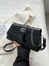 Cartera negra con textura símil cocodrilo, correa corta de cuero y correa larga de cadena plateada. Cierre con hebilla metálica.