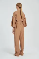 Mono largo color beige con cierre frontal, mangas abullonadas y cinturón con lazo.