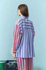 Camisa de algodón con diseño de rayas multicolor en tonos azul, amarillo y rojo. Presenta cuello clásico, cierre frontal con botones y mangas largas.