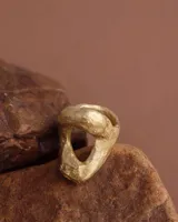 Anillo plateado con forma orgánica irregular y un agujero en el centro.