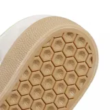 Championes Adidas modelo Gazelle ADV, con diseño clásico de perfil bajo. Presentan una capellada de gamuza en color beige claro, con las icónicas tres tiras laterales y refuerzo en el talón en color verde oscuro. Incluyen cordones blancos, suela de goma color caramelo y el nombre del modelo estampado en dorado en el lateral.