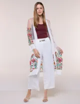 Cardigan tipo kimono largo de tul blanco semitransparente, con frente abierto y mangas largas. Presenta vistosos bordados florales multicolor en mangas, dobladillo y laterales.