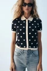 Chaqueta de punto de manga corta con estampado de corazones, cuello polo y cierre frontal con botones en forma de corazón.