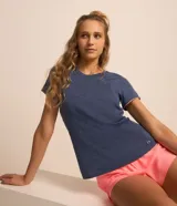 Remera deportiva femenina de poliamida color azul melange, con cuello redondo, manga corta y detalles de biés contrastante en tono rosado.