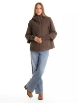 Tapado de tejido bouclé color marrón, con silueta evasé y largo a la cadera. Presenta cuello alto envolvente, cierre frontal oculto con botones a presión y bolsillos frontales de gran tamaño. Sus mangas son 3/4 con corte amplio y puños de tejido rib al tono que se extienden para cubrir las muñecas.