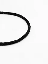 Vincha delgada de color negro, recubierta con pequeñas piedras brillantes que le otorgan una textura texturizada y elegante.