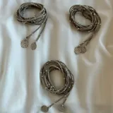 Corbatín largo color gris con pelotitas plateadas y dijes circulares.