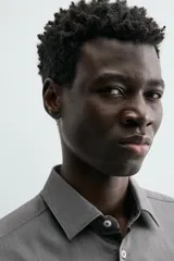 Camisa de hombre color beige claro, de corte slim fit, con cuello italiano, manga larga y cierre frontal de botonadura.