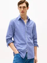 Camisa Tommy Hilfiger de hombre, de popelina de puro algodón con Flex Technology, con diseño de cuadros Vichy azules y blancos. Tiene cuello con botones, puños redondeados con botón, bolsillo de parche en el pecho y logo de Tommy Hilfiger bordado en el bolsillo.