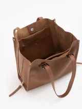 Bolso tipo tote de cuero color tostado con doble asa de hombro, detalles de hebillas metálicas en el frente y cierres laterales decorativos.