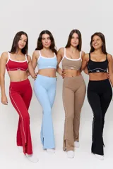 Conjunto deportivo compuesto por un top y un pantalón largo de corte acampanado, ambos en color rojo con detalles de líneas blancas. El top presenta breteles finos y el logo 'bk.' estampado en el frente. El pantalón cuenta con una línea lateral blanca y aberturas en el ruedo.