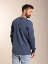 Remera blanca de manga larga con cuello redondo y logo bordado de un pájaro en el pecho.