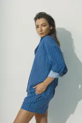 Camisa de corte relajado con diseño de rayas verticales en tonos rojos, marrones y blancos. Presenta cuello clásico, cierre frontal con botones al tono y mangas largas con puños que permiten un estilo arremangado.