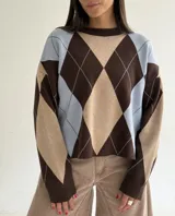 Sweater de punto con diseño de rombos en tonos marrón, beige y celeste, de corte holgado, cuello redondo y manga larga.