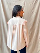 Camisa color rosa pálido con cuello babero bordado con calados y volados, mangas largas y lazo en el escote.