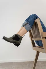 Botín negro de cuero con elásticos laterales, taco bajo y tirador trasero.