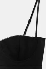 Top negro de estilo corsetero con escote corazón, copas definidas y tirantes finos ajustables. El bajo es redondeado.