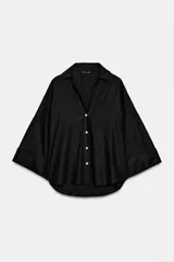 Camisa de corte holgado confeccionada en mezcla de lino, con cuello solapa, escote en pico y cierre frontal con botones. Presenta mangas amplias por debajo del codo con puños definidos.