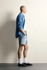 Shorts de denim de algodón con ajuste regular, diseño de cinco bolsillos y efecto lavado. Presenta cierre frontal con cremallera y botón, con el bajo acabado en corte irregular.