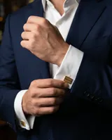 Gemelos rectangulares de acero con acabado dorado y textura estriada, diseñados para camisas de puño doble.
