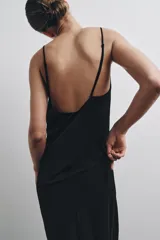 Vestido midi de color negro, con escote en pico y tirantes finos cruzados en la espalda.