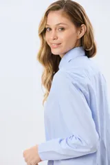 Camisa celeste rayada de corte holgado, con cuello camisero clásico y mangas largas.