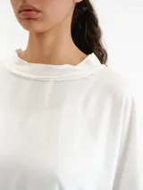Remerón blanco de corte holgado, mangas cortas amplias y cuello bote con jareta.