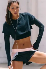 Camiseta deportiva negra de doble capa, con una capa interior ajustada de manga larga y una capa exterior corta y holgada de manga corta.