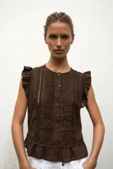 Blusa de cuello redondo y manga sisa con volantes, color marrón, con detalles de entredoses a tono, jaretas delanteras y cierre frontal con botones.