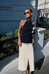 Top halter azul marino con detalles de ribetes en contraste color blanco en el cuello y el borde inferior, de diseño sin mangas y espalda descubierta con cierre de botones en el cuello.