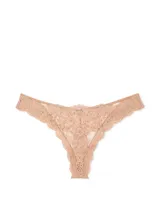 Bombacha tipo tanga de tiro bajo, confeccionada en encaje supersuave color tostado, con detalle de pequeña roseta decorativa en la parte frontal.