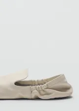 Zapatos tipo ballerinas planas de piel ovina en color blanco, con punta redonda, diseño sin cordones y detalle de fruncido elástico en el talón.