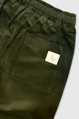 Pantalón de pana verde oliva con cintura elastizada y cordón de algodón. Cuenta con bolsillos laterales, un bolsillo trasero y el parche característico de Polonio.
