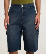 Bermuda de hombre en denim de algodón, modelo cargo, corte baggy y tiro medio. Presenta bolsillos laterales tipo cargo y cierre tradicional con botón y cremallera.