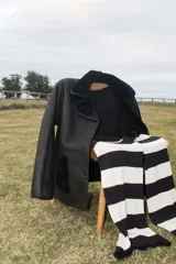 Gamulán de cuero negro con interior de piel sintética, corte oversize, solapas grandes, cierre frontal con botones y bolsillos laterales con apliques de piel.