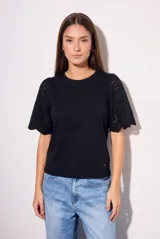 Remera de algodón peinado color negro, con mangas cortas de broderie con diseño calado y terminación festoneada. Presenta un corte oversize y cuello redondo.