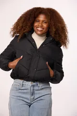 Campera bomber de nylon color rosado, con diseño acolchado, cierre frontal con cremallera y botones a presión, y capucha con borde de piel sintética al tono.