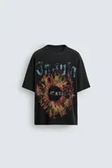 Camiseta de punto negro con efecto lavado, corte relaxed fit y cuello redondo. Presenta un estampado frontal con tipografía gótica en azul y una imagen circular que simula un iris en tonos rojizos y amarillos.