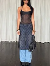 Conjunto de dos piezas color negro confeccionado en tul plumeti transparente con lunares. Incluye un top de escote recto con breteles finos y una falda midi de tiro bajo.