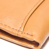 Billetera de cuero color tostado, de diseño clásico y rectangular, con el logo de la marca grabado en relieve en la esquina inferior derecha.