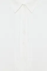 Vestido camisero de lino con cuello solapa, manga corta y cierre frontal con botones. Presenta un diseño con bajo redondeado y aberturas laterales.