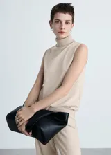 Top color beige de tejido de punto, cuello alto y sin mangas.