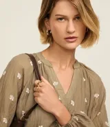 Vestido largo evasê color marrón con estampado de flores blancas, cuello en V, mangas largas abullonadas y cinturón de lazo.