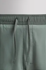 Shorts de entrenamiento azul marino con calza interior negra. Cintura elástica ajustable con cordón, bolsillos laterales con cierre y aberturas laterales en el bajo.