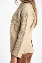 Sweater de punto con diseño de trenzas verticales, cuello redondo y corte oversize. Presenta puños y ruedo acanalados anchos.